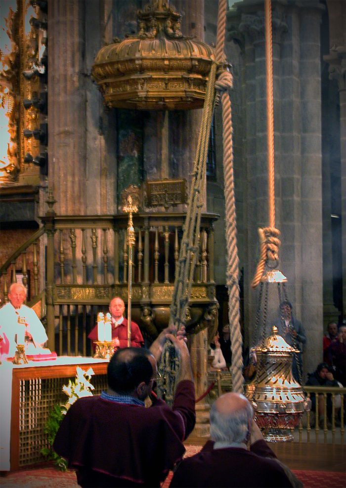 This is the Botafumeiro (Galician for "smoke expeller"), a giant incense metal container that is swung over the people during the Mass from a suspended pulley mechanism in the dome on the roof of the church.